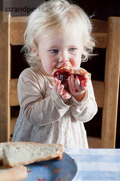 Weibliches Kleinkind beim Brot und Marmelade essen