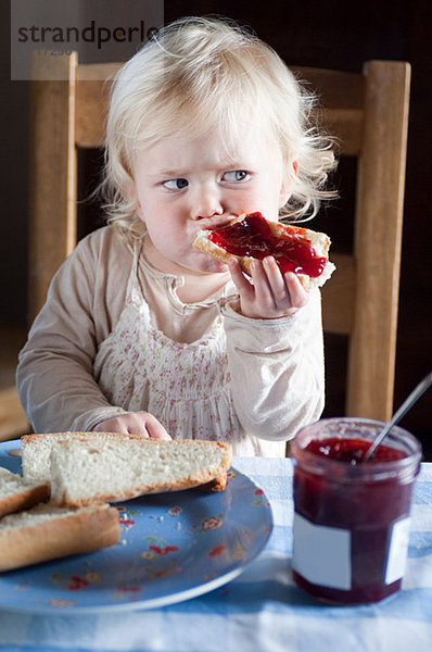 Weibliches Kleinkind beim Brot und Marmelade essen