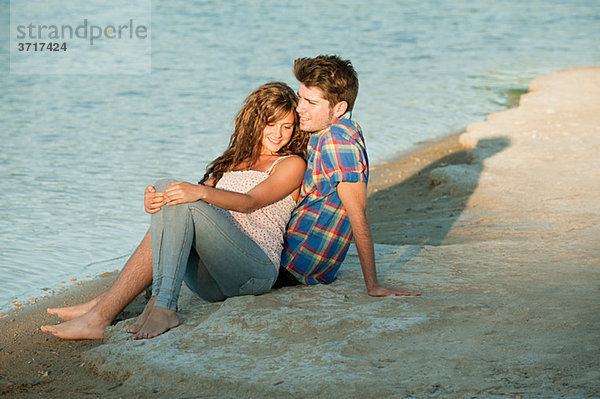 Junges Paar am See sitzend