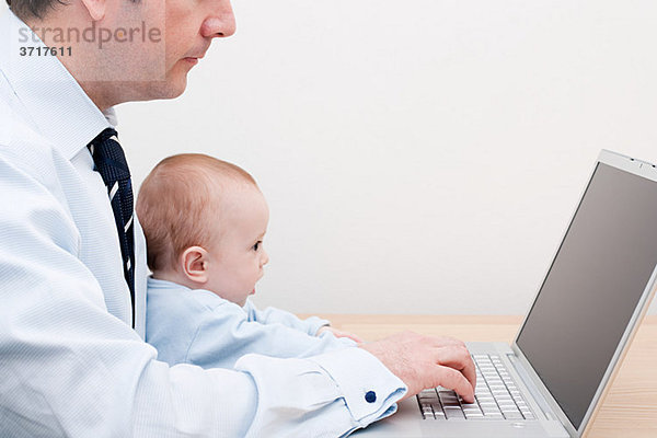 Arbeitender Vater und Baby am Laptop