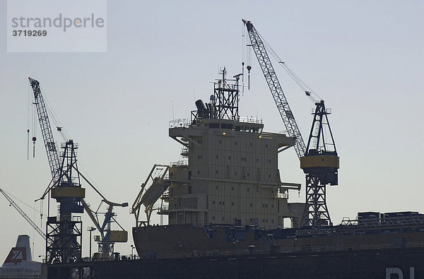 Werftkräne und die Aufbauten eines Containerschiffes ragen in den Himmel über der Werft Blohm und Voss im Hamburger Hafen