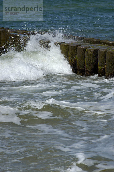 Wellen brechen sich an einer Buhne am Ostseestrand