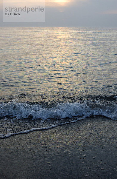 Sanfte Wellen schlagen im Abendlicht an den Strand