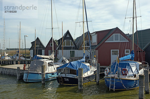 Segelboote liegen vor Bootshäusern im Hafen von Althagen bei Ahrenshoop