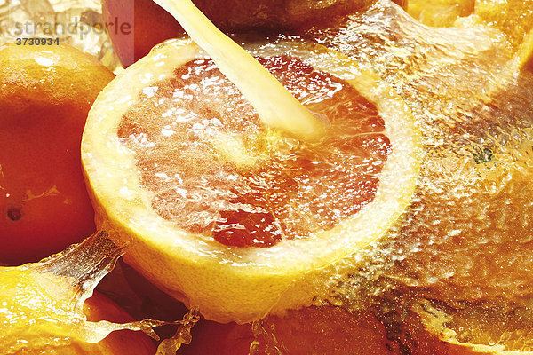 Zitrusfrüchte unter Fruchtsaft-Strahl  Orangen  Zitronen