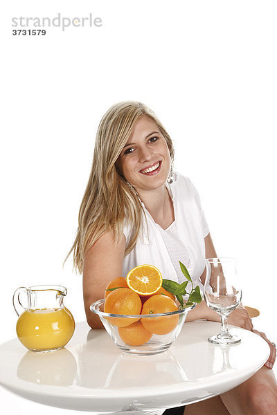 Junge Frau  Bartisch mit Orangen und Orangensaft