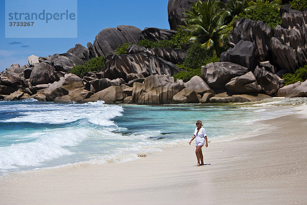 Eine Frau läuft am Strand von Grand Anse mit den typischen Granitfelsen von La Digue  Indischer Ozean  Insel La Digue  Seychellen  Indischer Ozean  Afrika