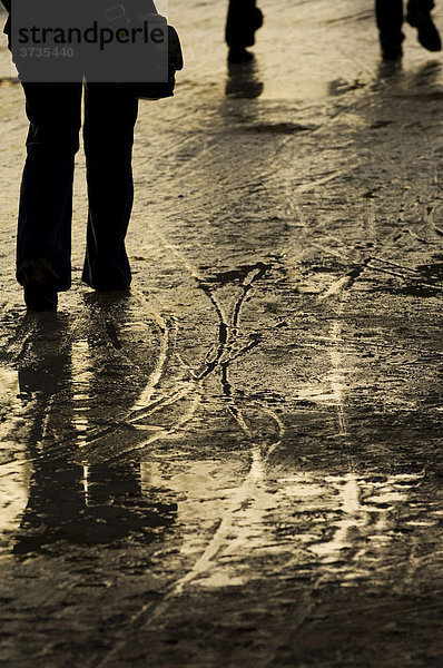 Wasserpfützen  Reifen- und Fußspuren nach einem Regen