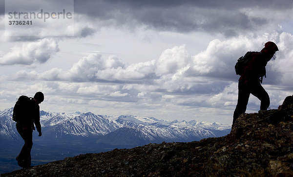 Silhouette zweier junger Frauen beim Wandern  Berg Mt. Lorne und Berge des Pacific Coast Gebirges dahinter  Yukon Territory  Kanada  Nordamerika