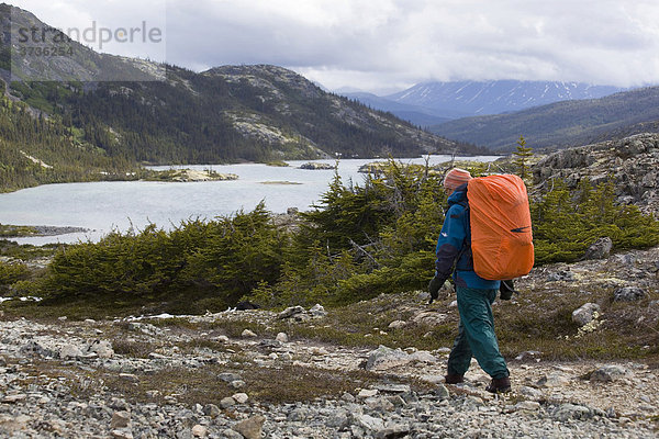 Wanderin  Rucksackreisende wandert durch die alpine Landschaft  hinten der Deep Lake Zeltplatz  Chilkoot Trail  Chilkoot Pass  Yukon Territory  British Columbia  Kanada