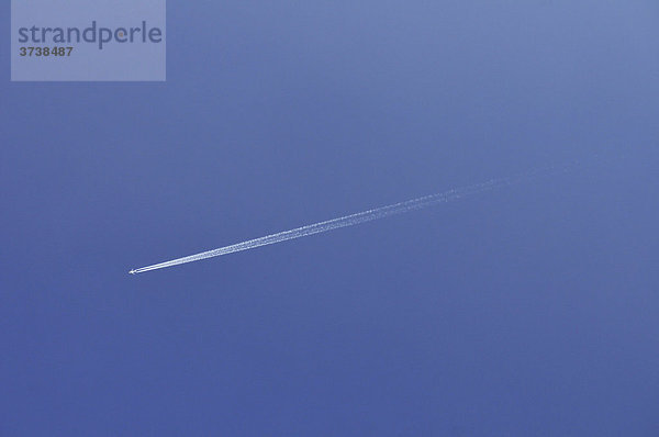 Flugzeug mit Kondensationsstreifen vor blauem Himmel