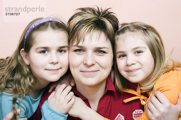 Lächelnde Mutte  36 Jahre alt  mit ihren beiden Töchtern  10 und 6 Jahre alt  drinnen