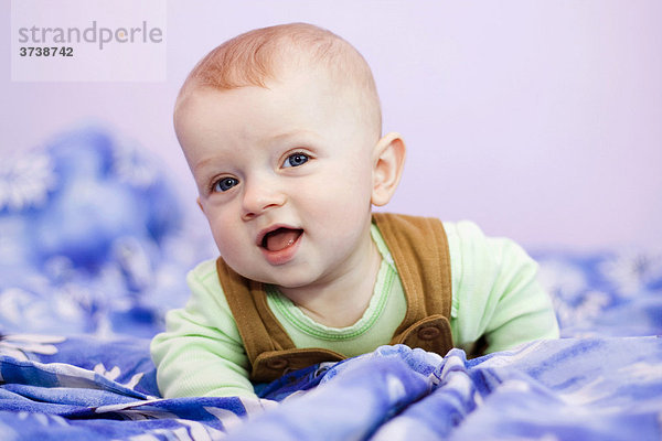 Lächelnder kleiner Junge  7 Monate alt  auf dem Bett