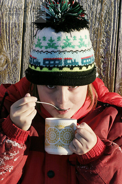 Mädchen  9 Jahre  mit Wollmütze  trinkt Tee  draußen