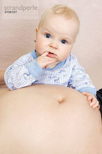 Baby  7 Monate  mit dem Bauch der schwangeren Mutter