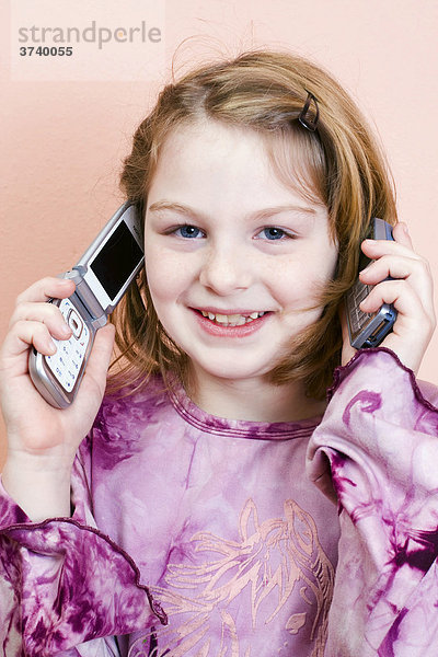 Neunjähriges Mädchen mit zwei Telefonen