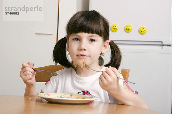 Sechsjähriges Mädchen isst mit Messer und Gabel