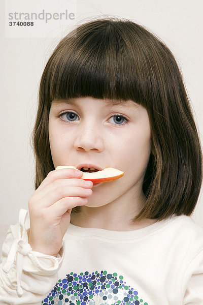 Sechsjähriges Mädchen isst einen Apfel