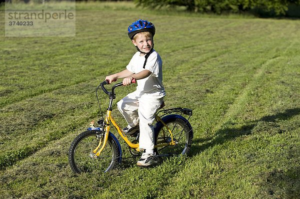 Kind  kleiner Junge  4 Jahre  mit Fahrrad und Helm auf Wiese