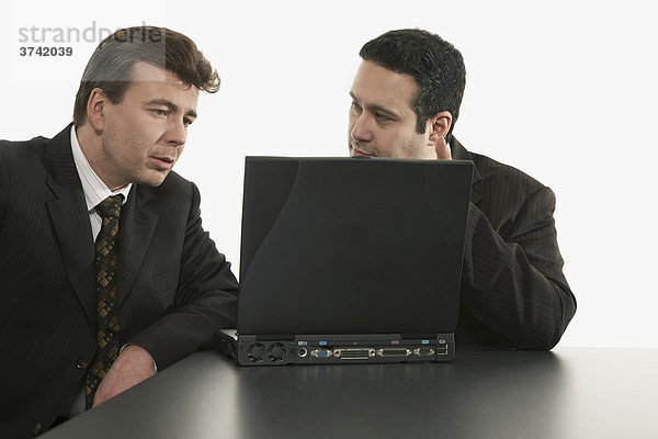 Zwei Geschäftsleute sitzen hinter einem Laptop