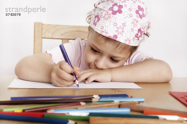 6jähriges Mädchen sitzt malend am Schreibtisch