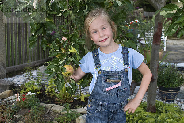 Mädchen  5 Jahre  steht unter einem kleinen Apfelbaum
