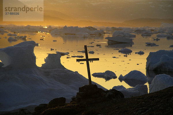 Christliches Kreuz vor Eisbergen im orangen Abendlicht  Parnakajiit  Sermilik Fjord  Ost-Grönland  Arktis