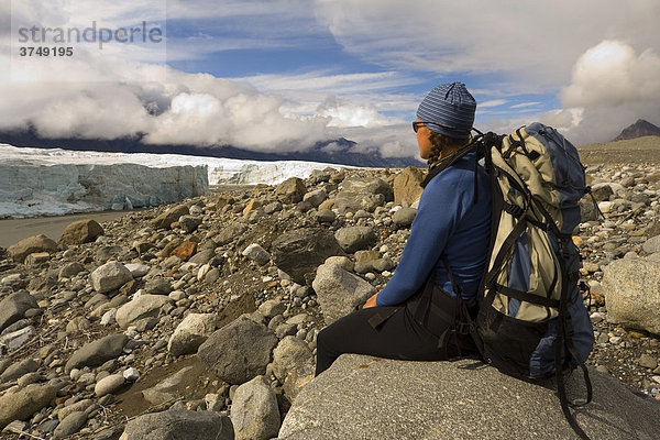 Junge Frau  Rucksacktouristin  Bergsteigerin genießt die Aussicht am Donjek Gletscher  St. Elias Gebirge  Donjek Route  Kluane National Park  Yukon Territory  Kanada  Nordamerika