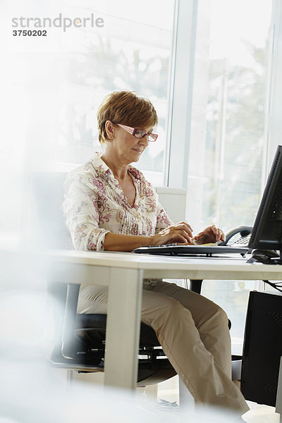 Frau mittleren Alters bei der Arbeit am Computer