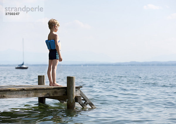 Junge stehend auf Pier mit Schwimmgürtel