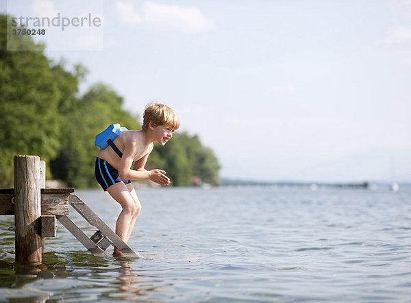 Junge springt im Wasser mit Schwimmgürtel