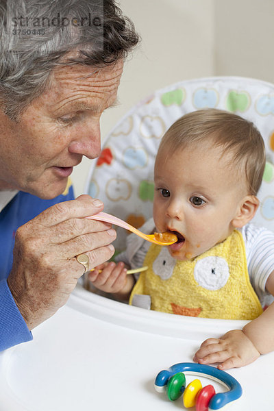 Opa füttert Enkel mit Babylöffel