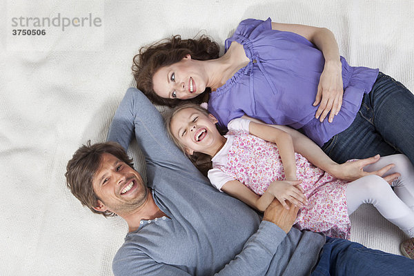 Glückliche Familie auf dem Teppich liegend
