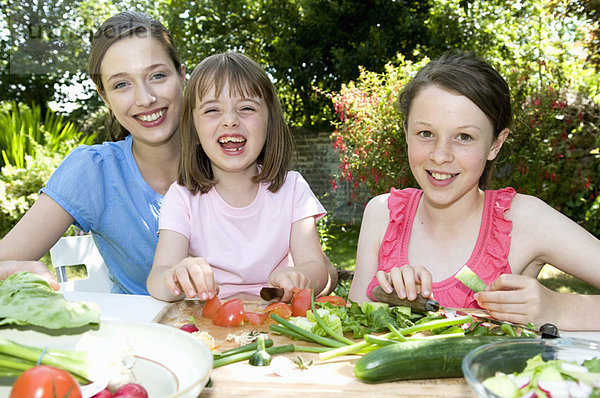 Glückliche Mutter und Töchter bereiten das Essen zu.