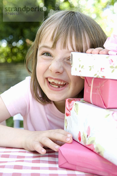 Ein fröhliches kleines Mädchen  das gerade Geschenke aufmacht.