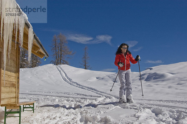 Junge Frau fährt auf Ski an Hütte mit Eiszapfen vorbei  Hinterstoder  Österreich