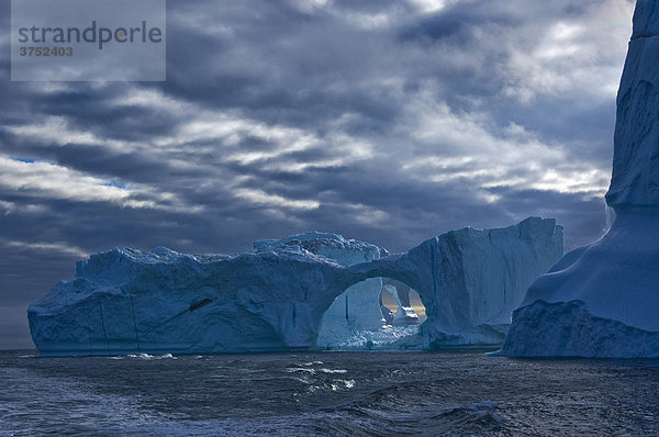 Eisberg mit Eistor bei dramatischer Wolkenstimmung  Diskobucht  Nordatlantik  Grönland