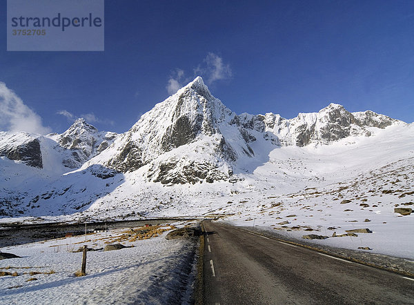 Straße vor gebirgiger Winterlandschaft auf den Lofoten  Norwegen  Skandinavien