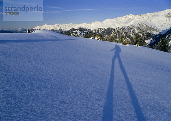 Langer Schatten eines Skitourengehers fällt auf ein Schneefeld  hinten Gipfel der Ötztaler Alpen  Tirol  Österreich  Europa
