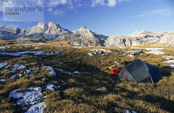 Ein grünes Zelt  gelber Rucksack  rote Daunenjacke und Gaskocher in herbstlicher Berglandschaft  Gröden  Südtirol  Italien  Europa
