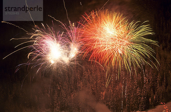 Feuerwerk vor verschneitem Fichtenwald