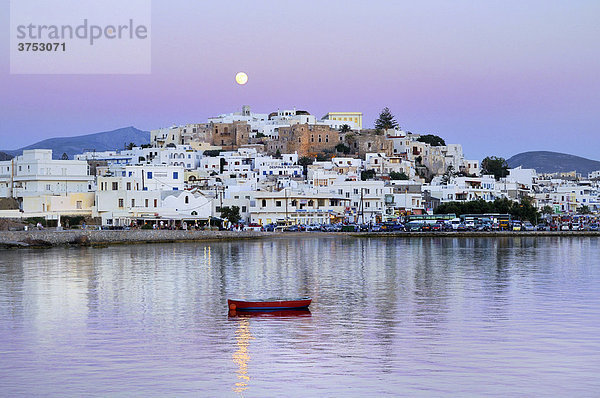 Weiße Häuser  Vollmond im rosa Abendhimmel über Naxos Stadt mit Kastro  venezianische Festung  rotes Holzboot im Meer  Kykladen  Griechenland  Europa