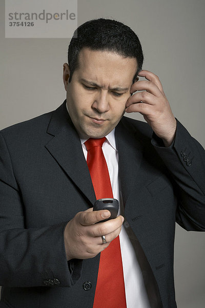 Mann blickt nachdenklich auf die Informationen seines Handy