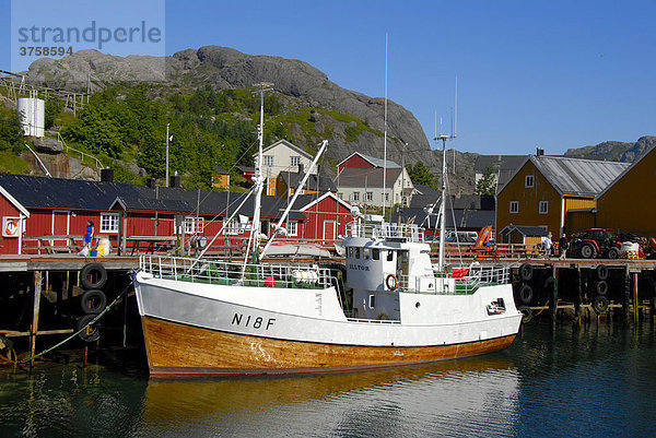 Schiff im kleinen Hafen mit roten Fischerhäusern  Rorbuer (Rorbu) Häuser von Nusfjord  Lofoten  Norwegen  Skandinavien
