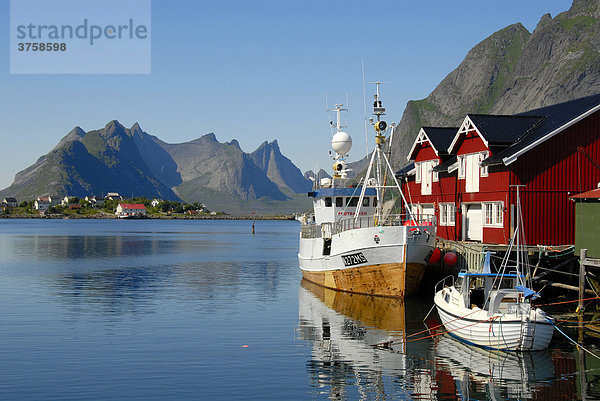 Blick über den Fjord mit Booten und Fischerhäusern  Rorbuer (Rorbu) Häuser auf die Berge von Moskenesoya  Reine Hamnöy  Lofoten  Norwegen  Skandinavien