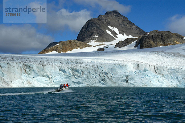 Kleines Motorboot vor großer Eiswand des Apusiak Gletschers und Gebirge  Ostgrönland  Arktis