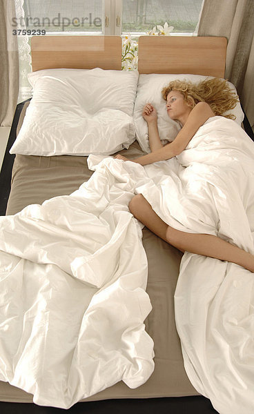 Schlafende Frau allein im Doppelbett