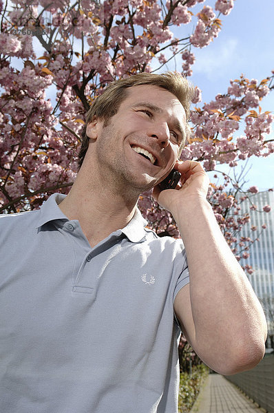 33-jähriger Mann beim Telefonieren im Frühling