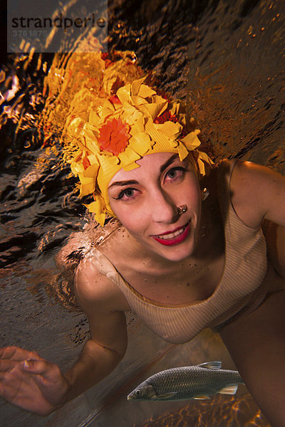 Frau im 50er Jahre Badekleid und mit gelber vintage Badekappe Unterwasser  Barsch