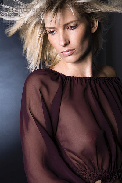 Portraitaufnahme einer jungen  blonden Frau mit durchsichtiger Bluse